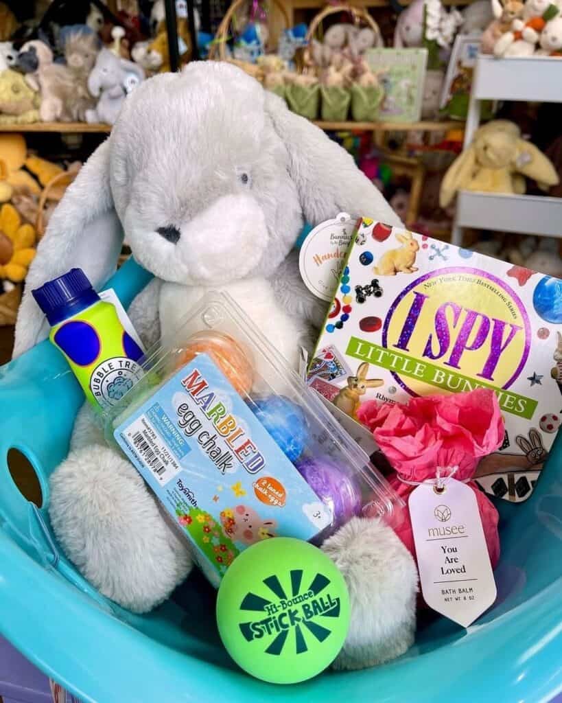 Bucket filled with open ended okay toys such as frisbee, egg chalk, I spy booklet and paint